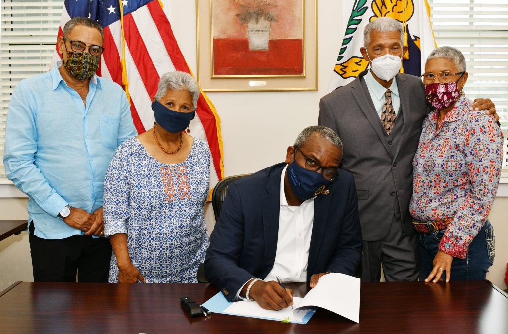 Governor Albert Bryan Jr. signs legislation naming the University of the Virgin Islands campus on St. Thomas after Dr. Orville Edward Kean, who attended the bill-signing with his family